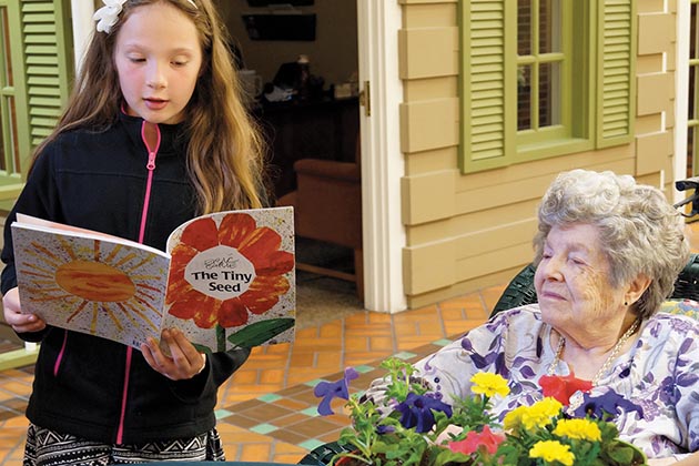 child reading to senior citizen
